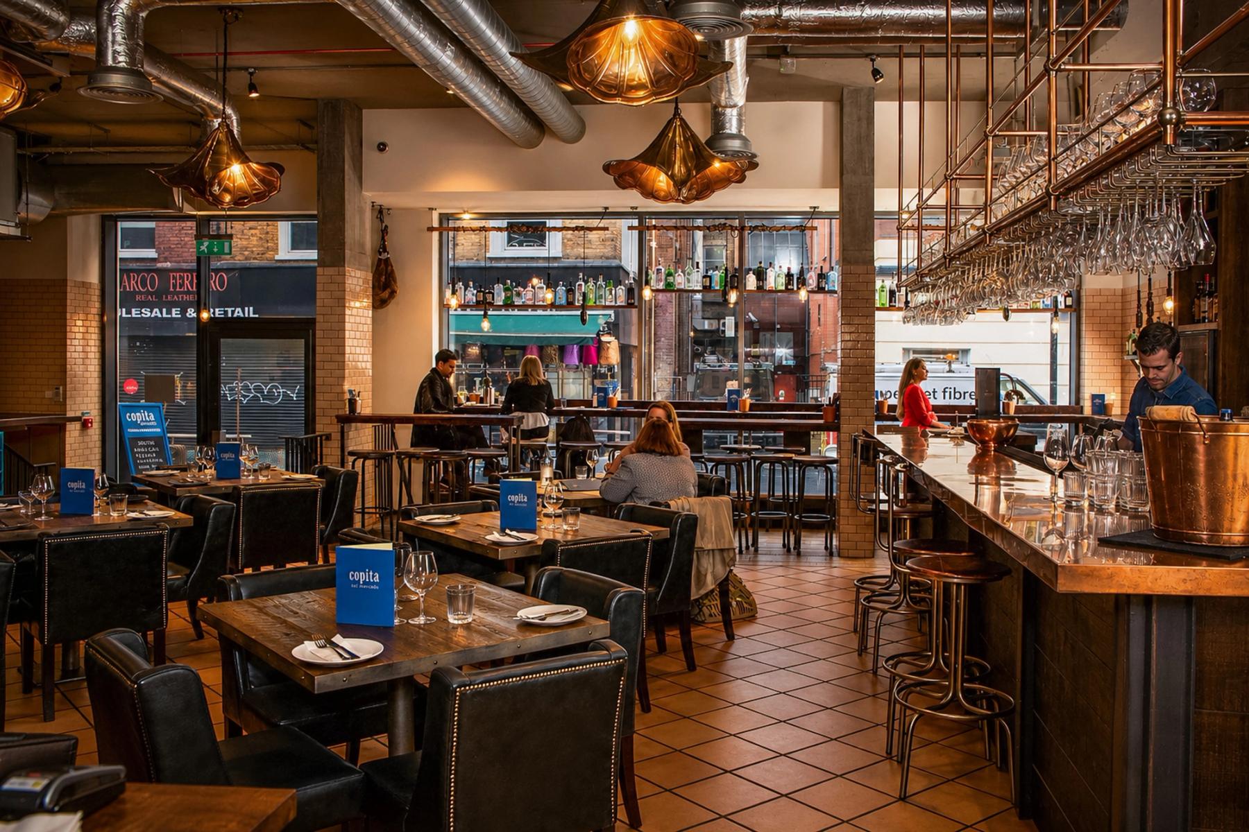 Interiorul restaurantului Copita din Soho, Londra — bar cu blat de cupru, lustre vintage și menus pe mese, fotografie de ședință editorial