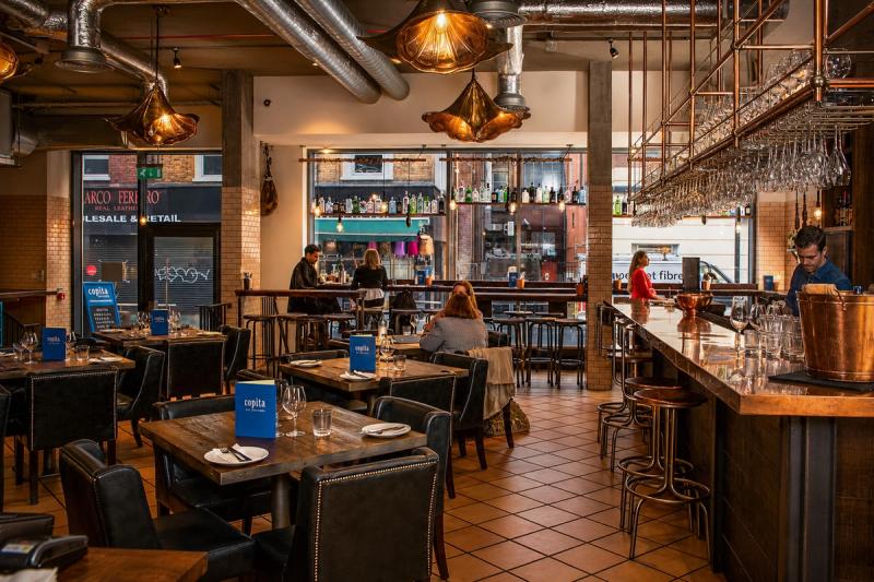 Interiorul restaurantului Copita din Soho, Londra — bar cu blat de cupru, lustre vintage și menus pe mese, fotografie de ședință editorial