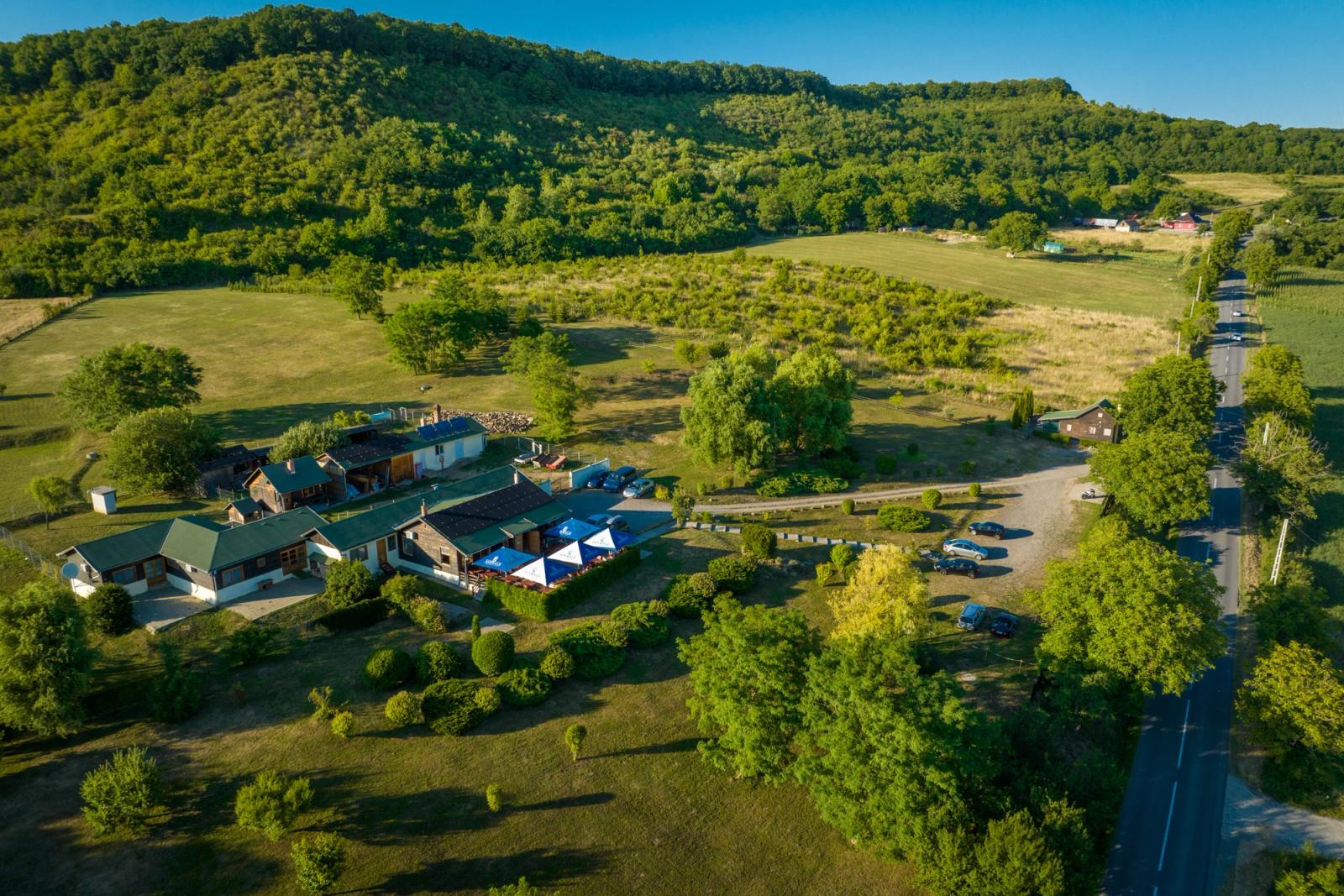 Vedere aeriană cu drona — toată proprietatea Schwabenhof: clădiri, terasa cu umbrele, parcare și drum de acces în Isla, Transilvania.
