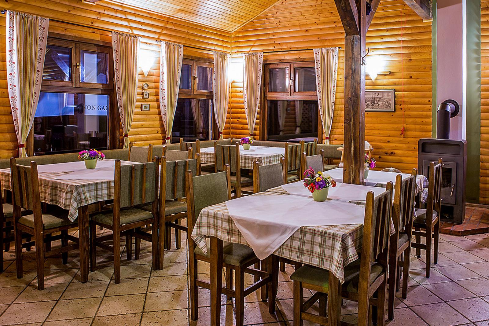 Interior restaurant rustic cu sobă pe lemne și fețe de masă tradiționale