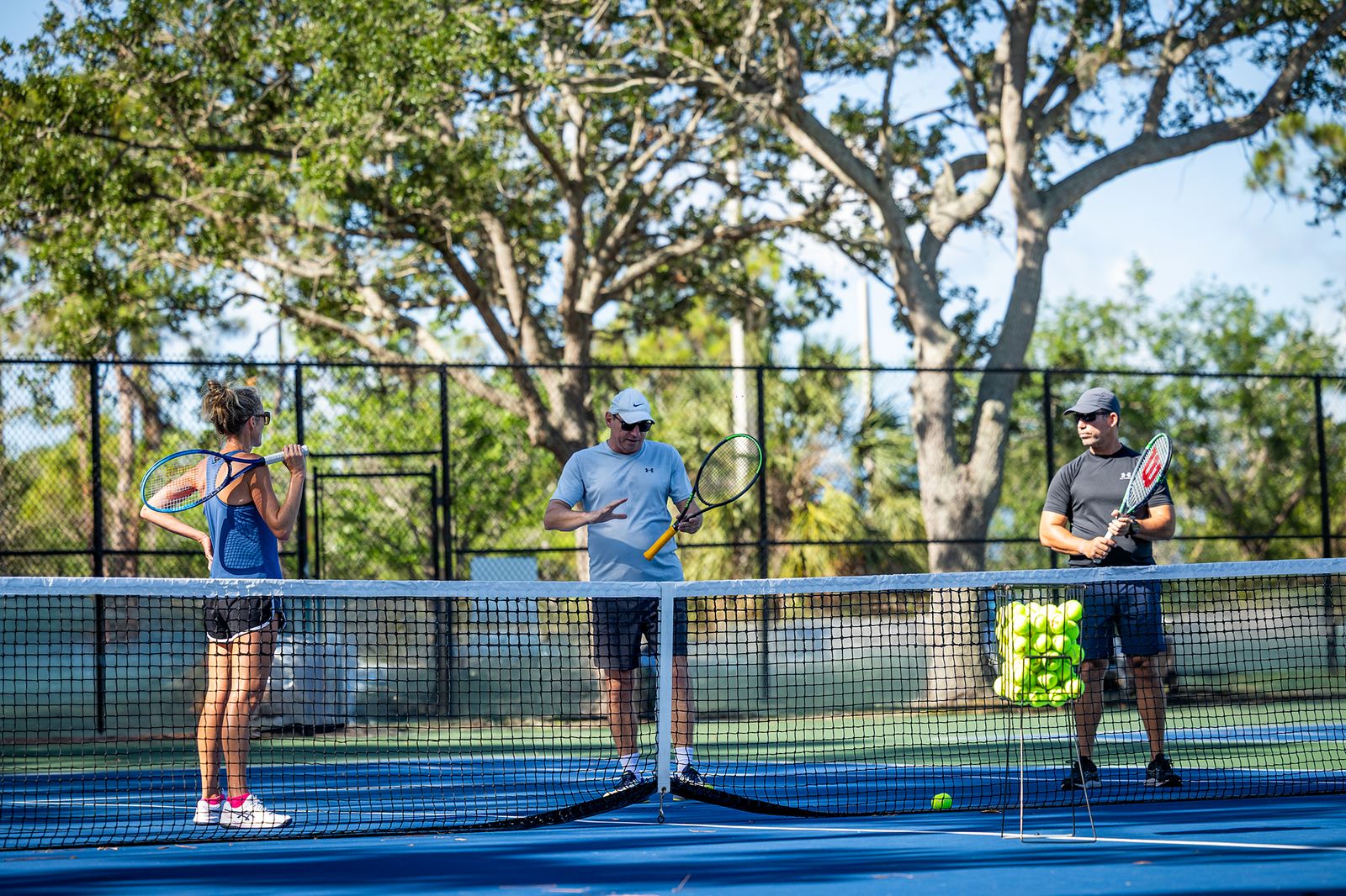 Coach Top Spin Academy în plină explicație tehnică pentru două persoane pe teren, Sarasota, Florida.