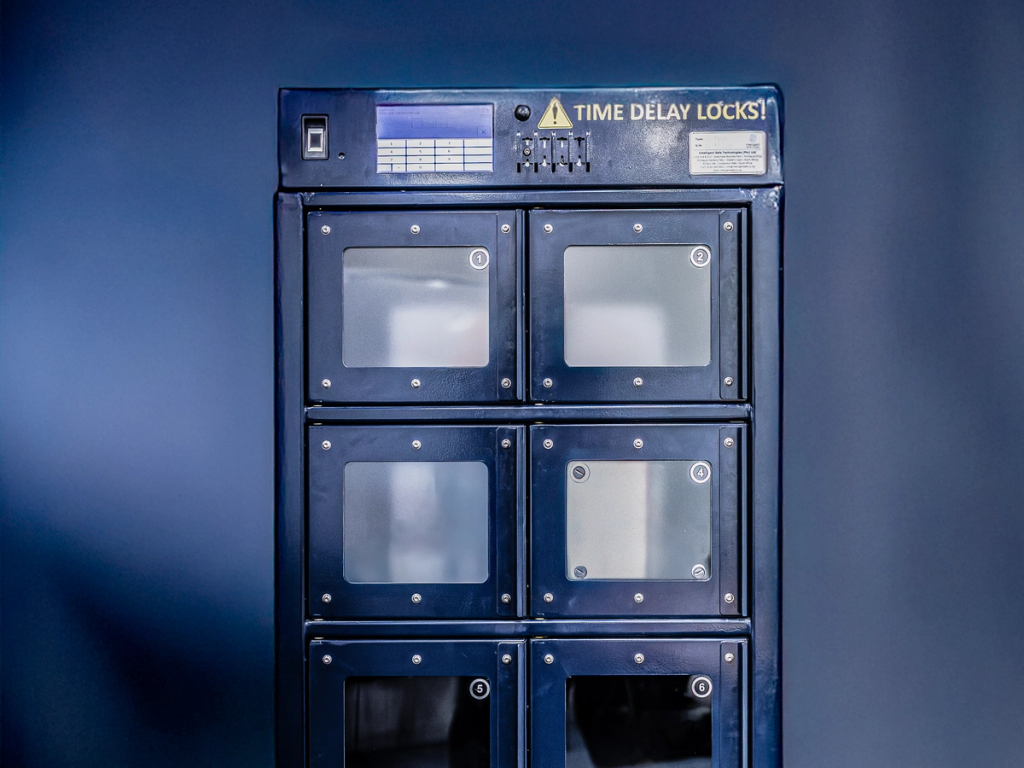 A blue security locker with six compartments, labeled "TIME DELAY LOCKS," featuring a digital display and control panel on top.