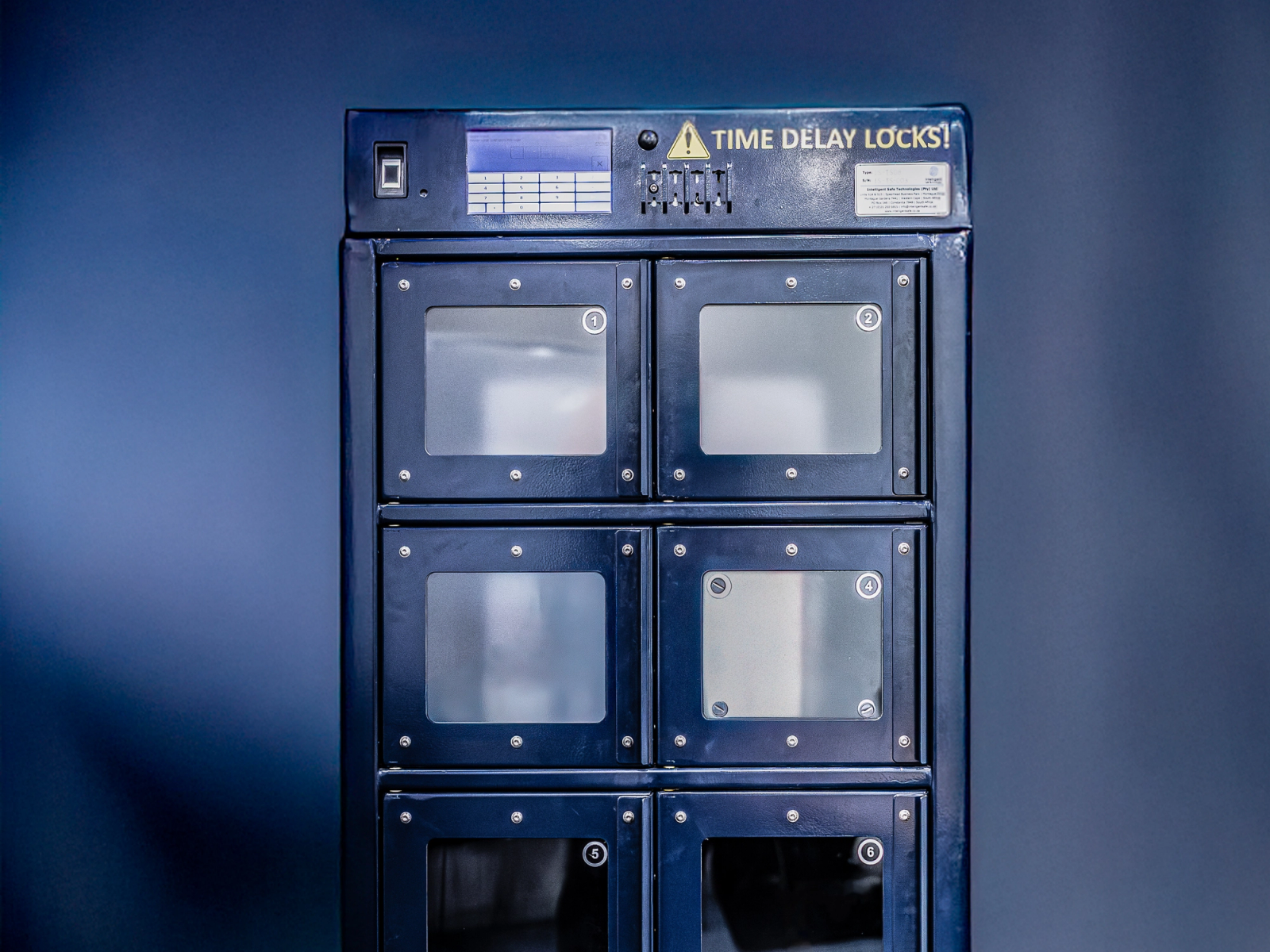 A blue security locker with six compartments, labeled "TIME DELAY LOCKS," featuring a digital display and control panel on top.