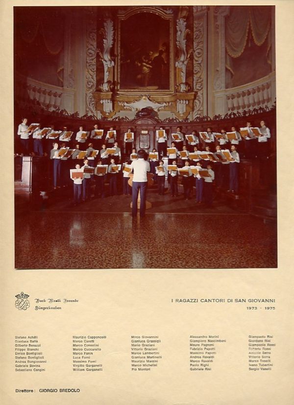 Cartoncino con la foto ufficiale: i ragazzi in camicia bianca cantano con le cartelline aperte nell’abside di una chiesa; sotto, la scritta “I Ragazzi Cantori di San Giovanni 1973-1975”, i nomi dei coristi e quello del direttore, Giorgio Bredolo