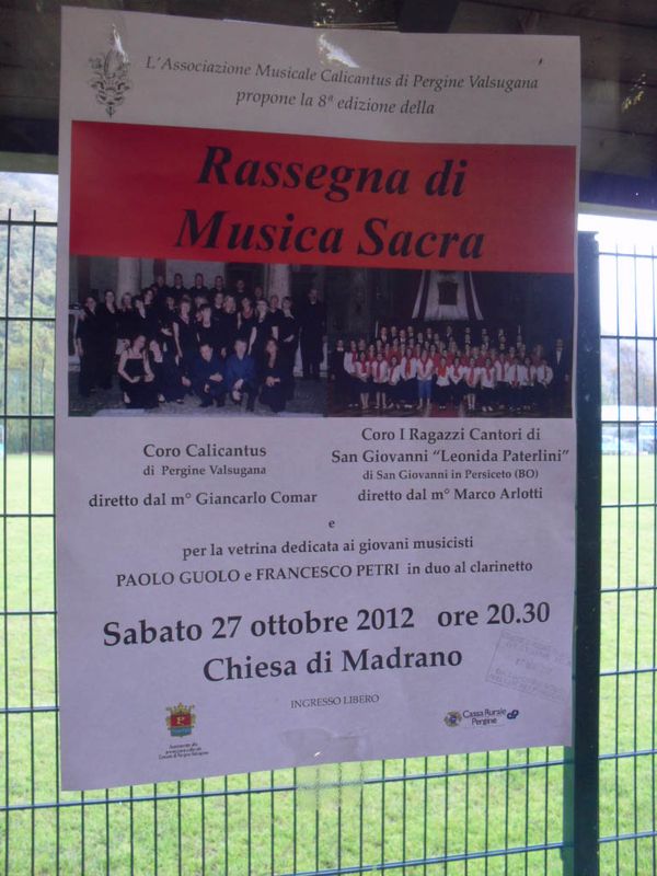 Locandina affissa a una recinzione: l’8ª Rassegna di Musica Sacra con il Coro Calicantus, i Ragazzi Cantori e un duo di clarinetti, sabato 27 ottobre 2012 alle 20.30 nella chiesa di Madrano