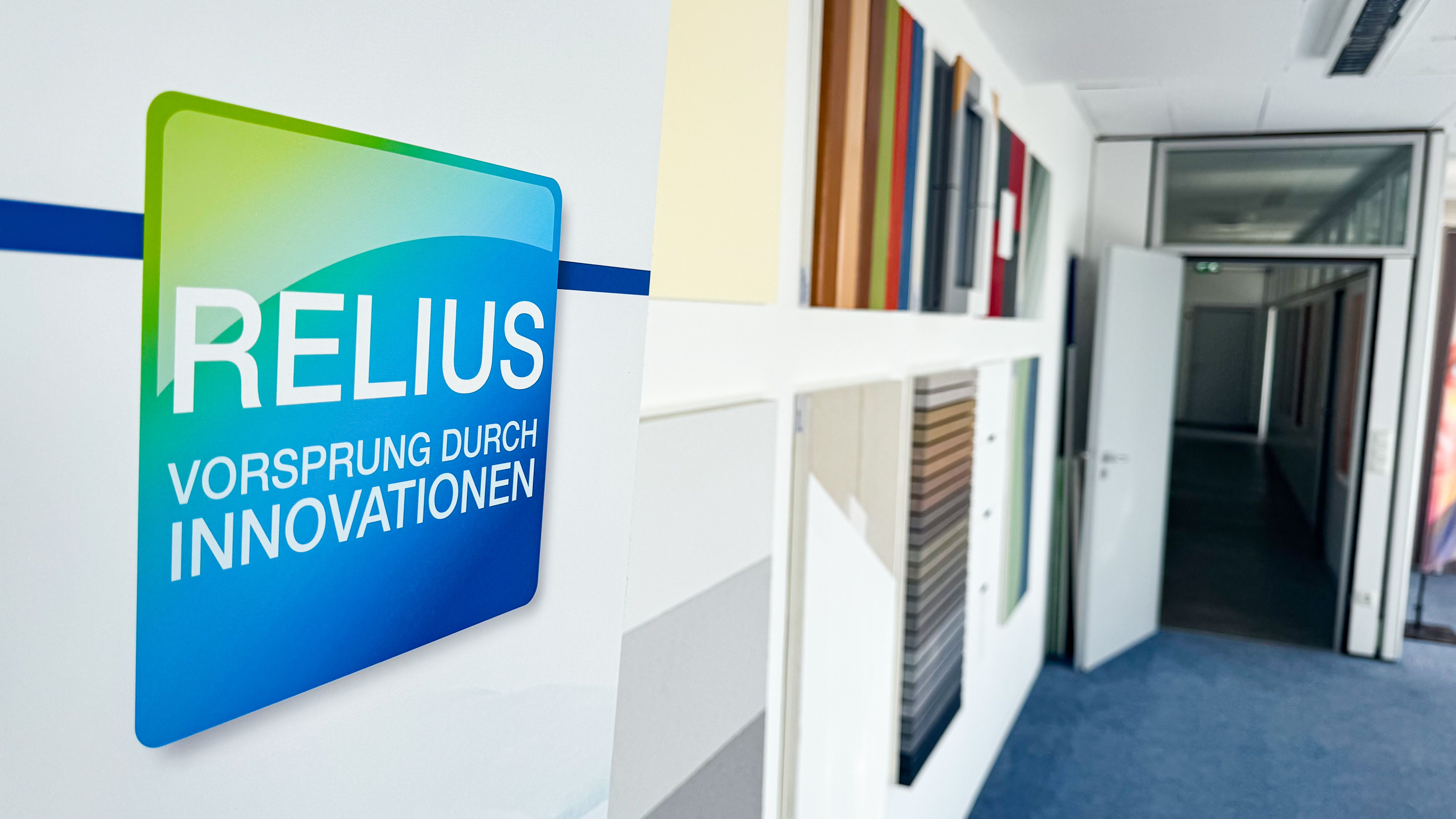 Wand mit Musterplatten in verschiedenen Farben und Oberflächen im RELIUS-Schulungsbereich.