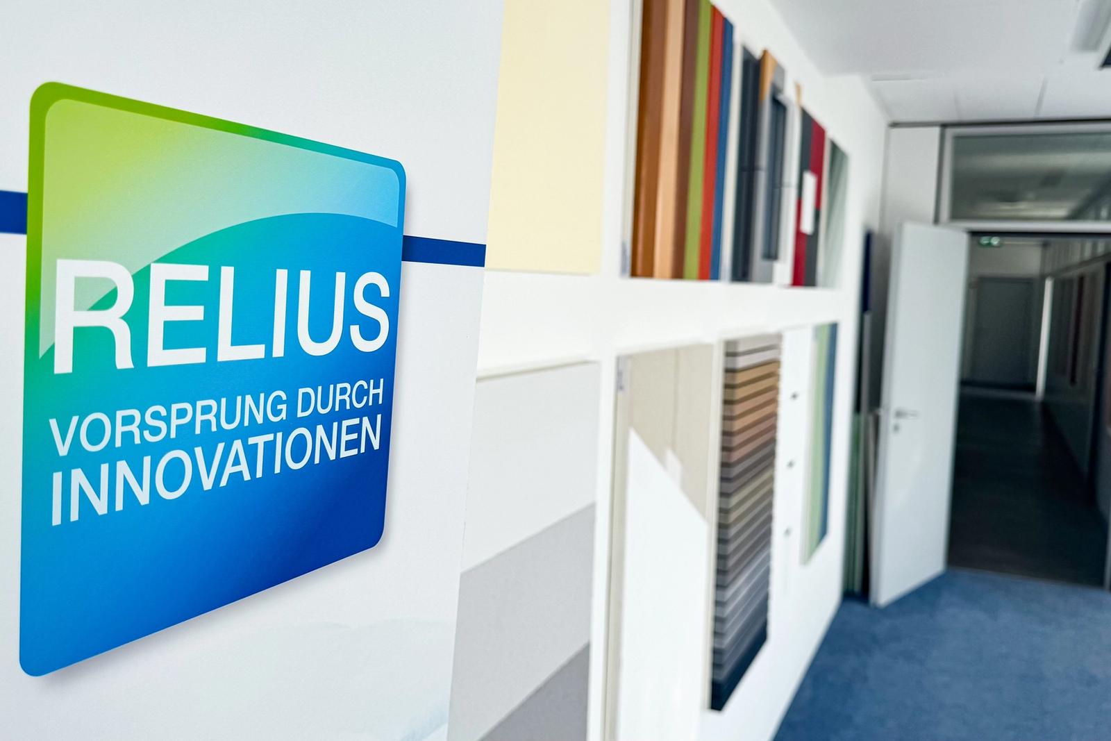 Wand mit Musterplatten in verschiedenen Farben und Oberflächen im RELIUS-Schulungsbereich.