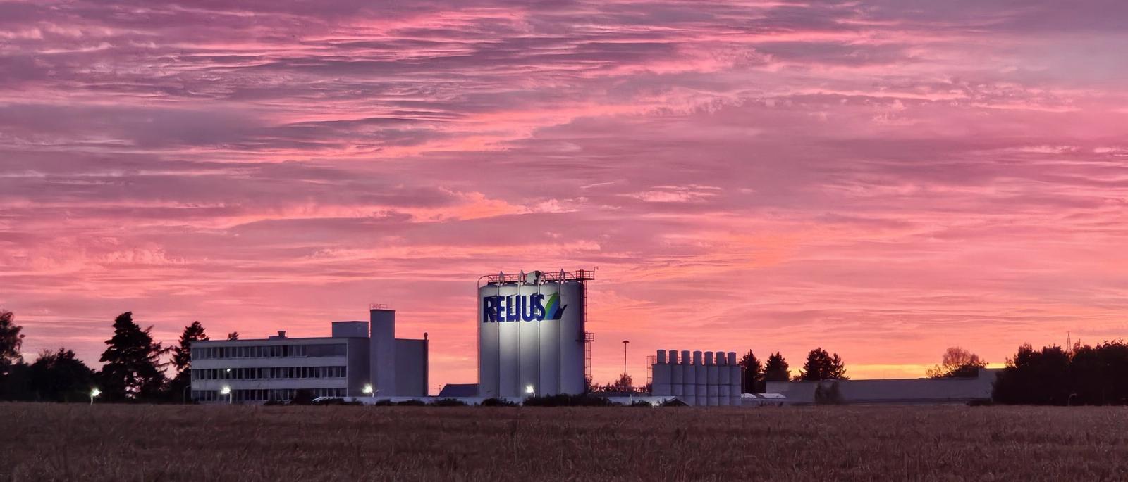 RELIUS Werk in Memmingen bei Abendrot, beleuchtetes Silo mit RELIUS Logo