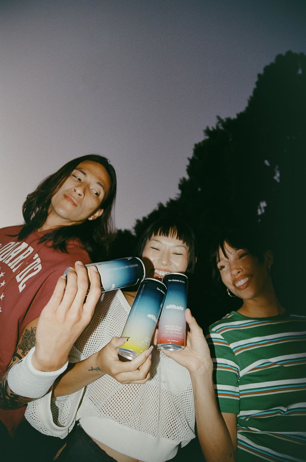Three people holding cans of Altitude