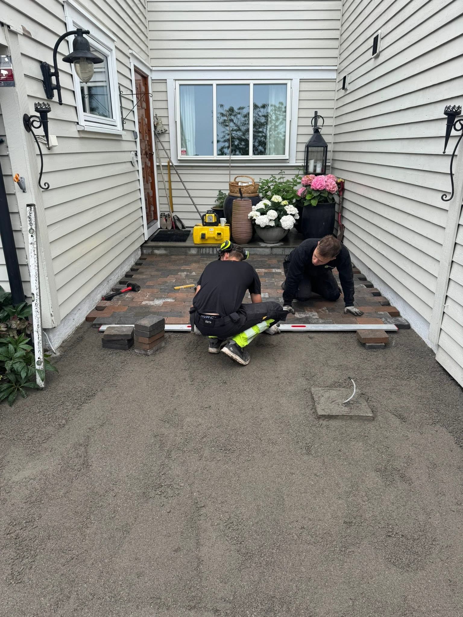 To anleggsgartnere legger heller i en smal passasje mellom hus