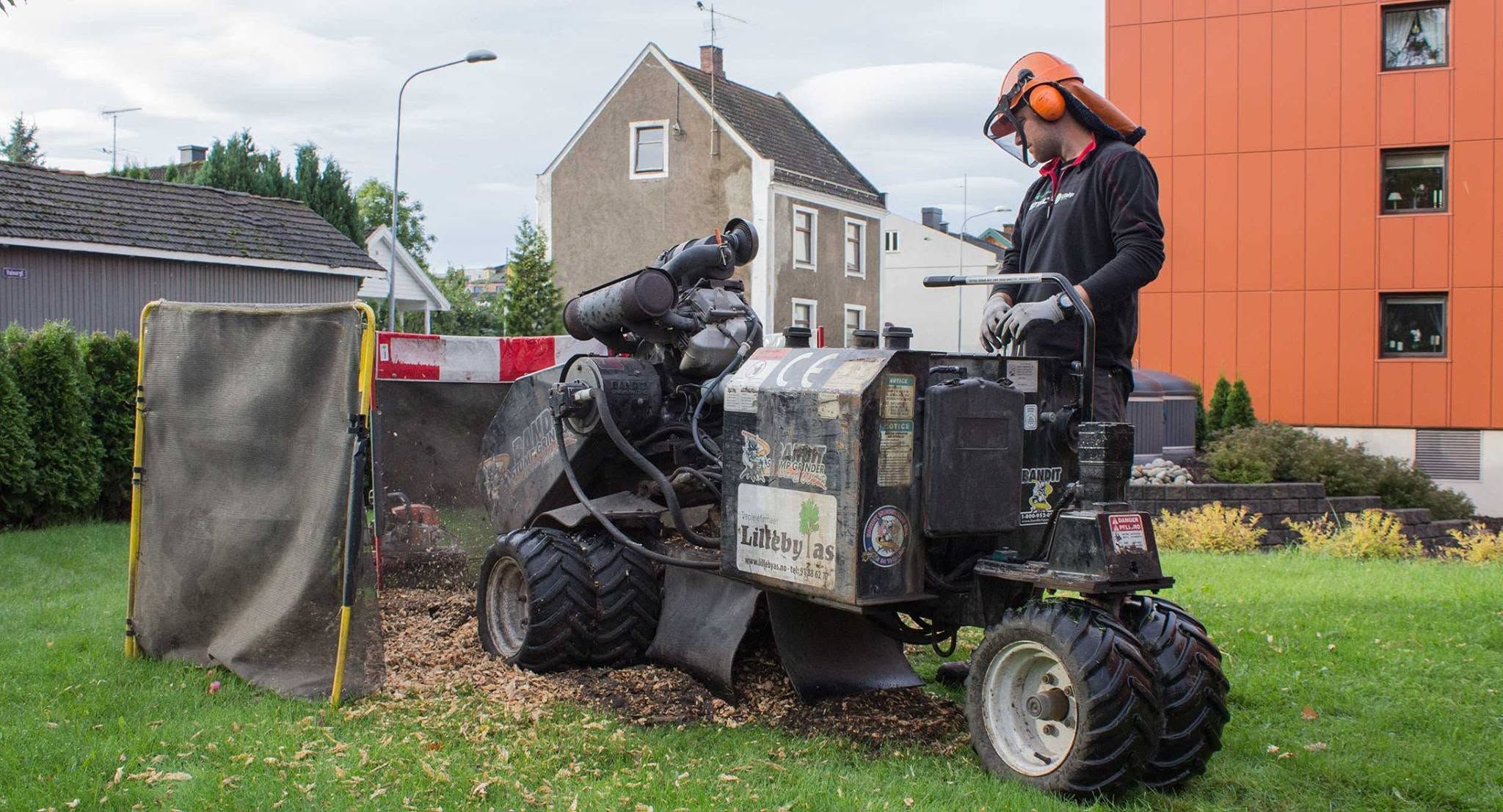 Stubbefreser med verneskjerm i arbeid på en plen