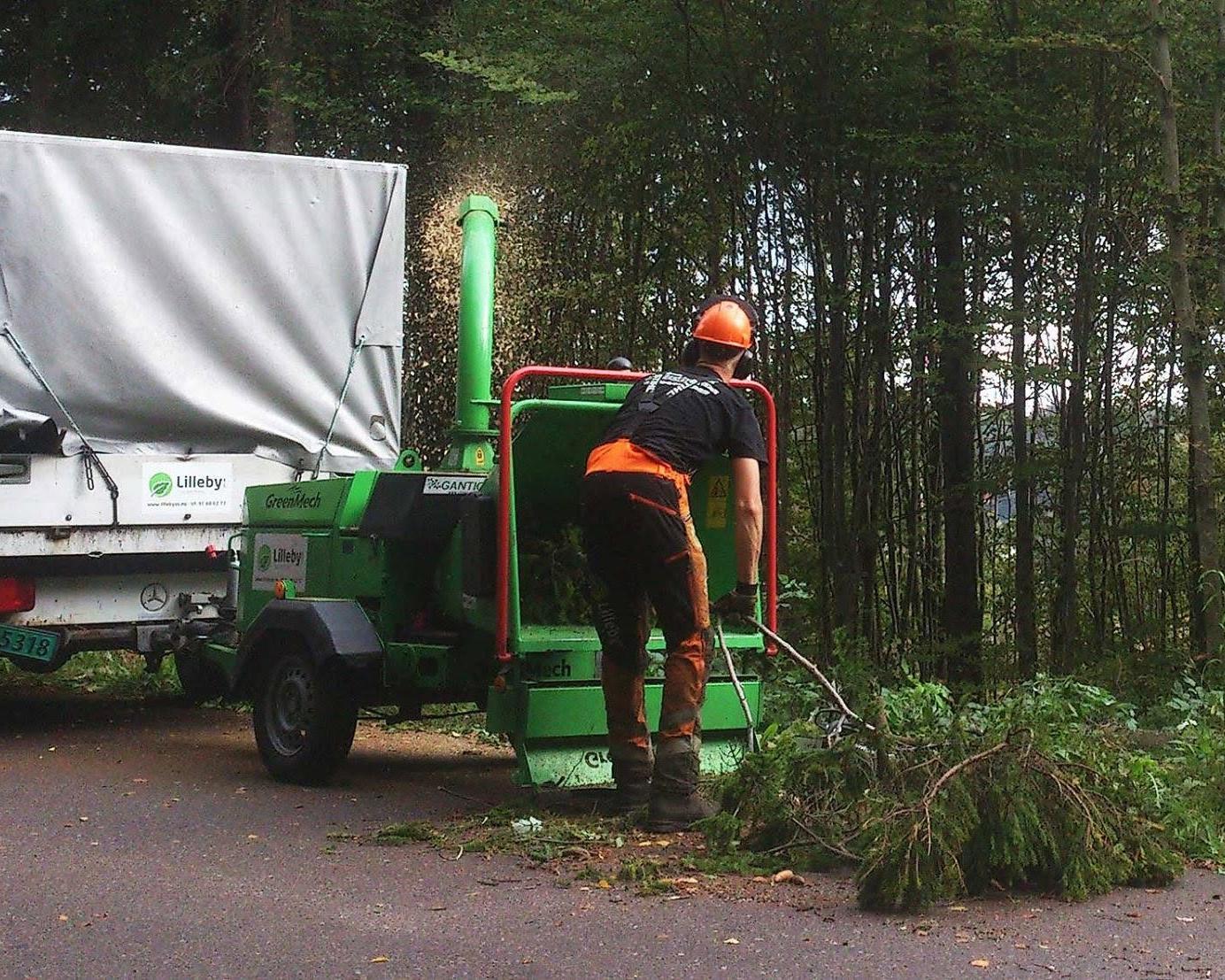 Flishugger i arbeid i skogkanten ved lastebilen