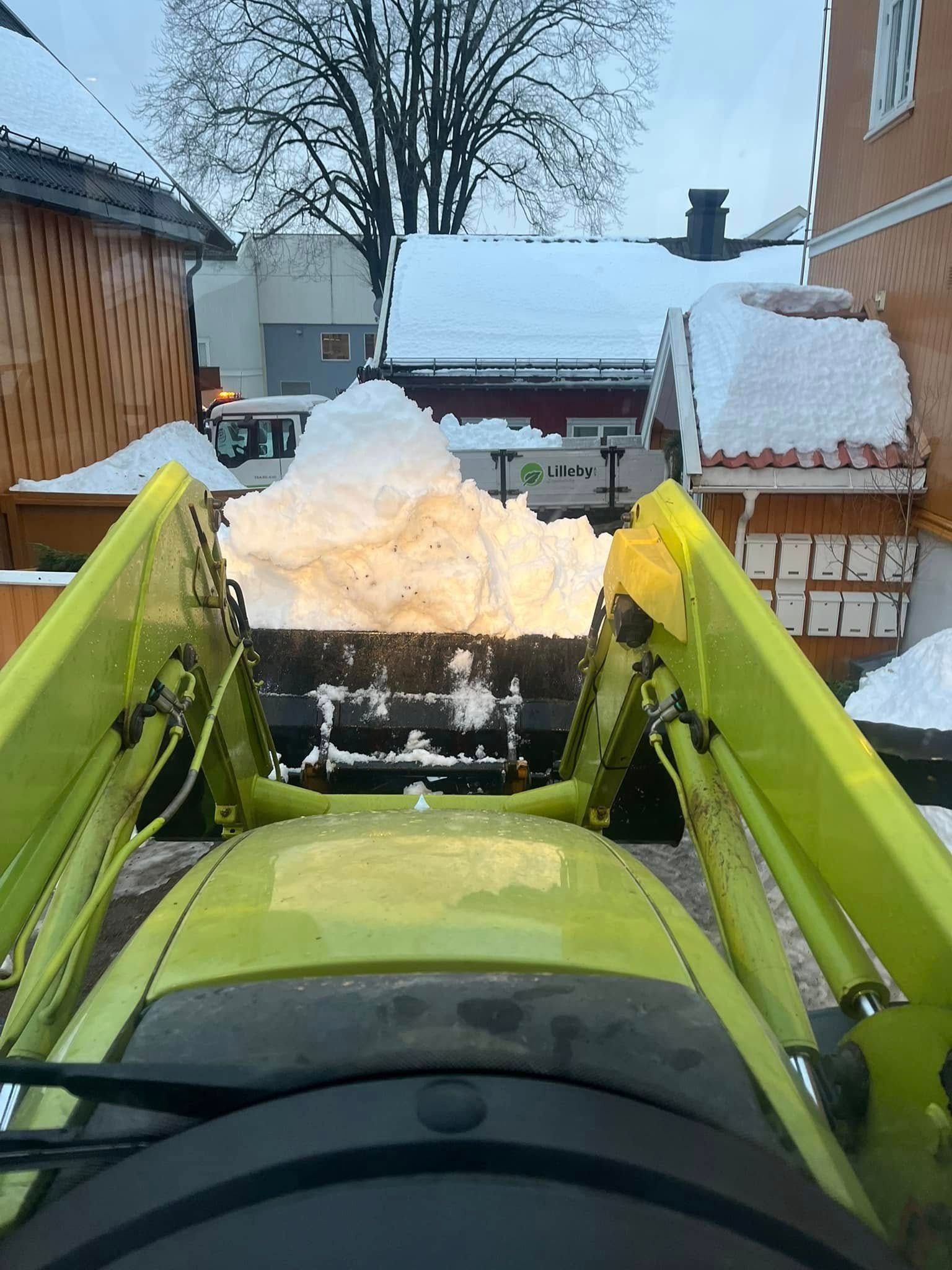 Hjullasteren tømmer en skuff med snø ved et boligbygg