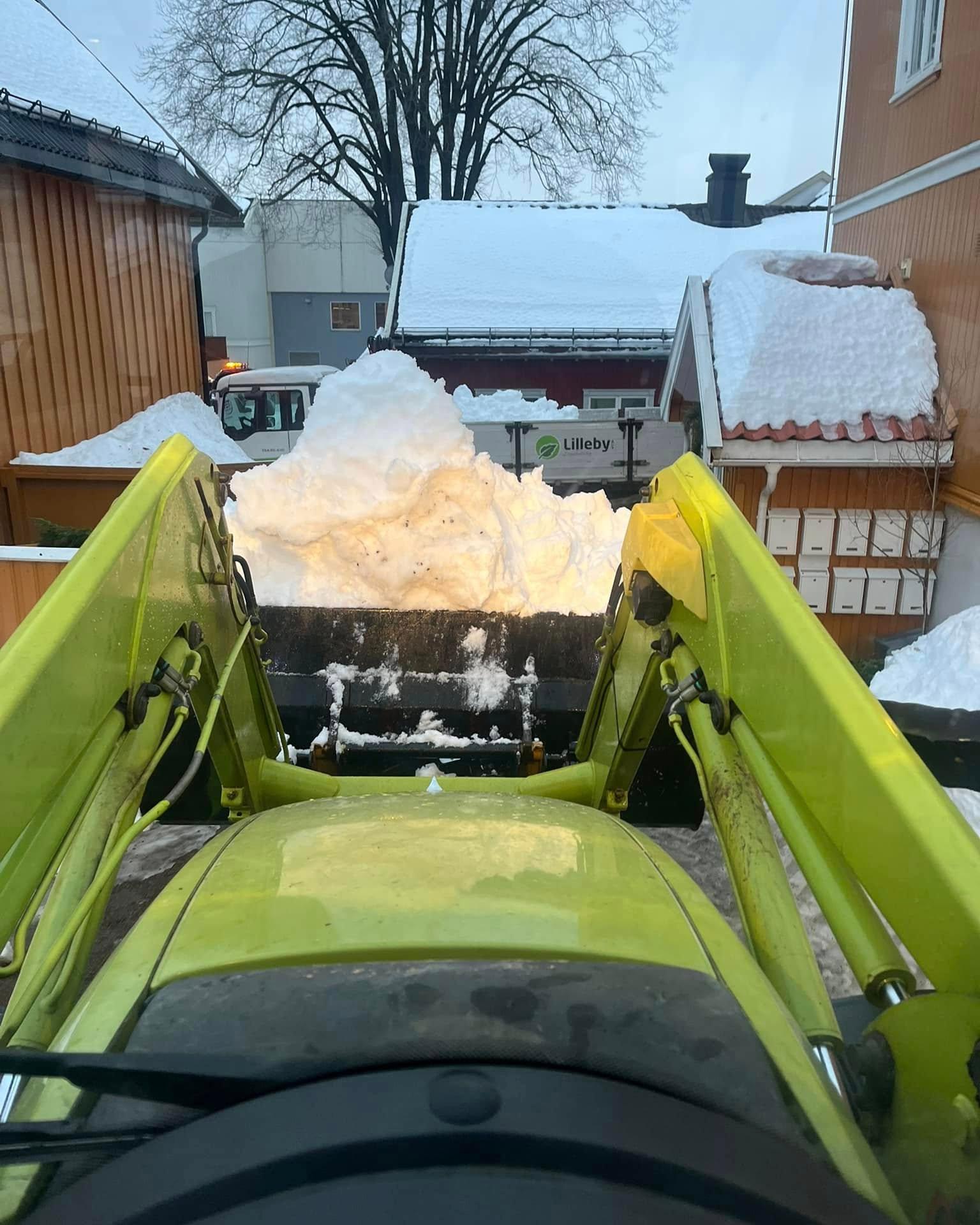 Hjullasteren tømmer en skuff med snø ved et boligbygg