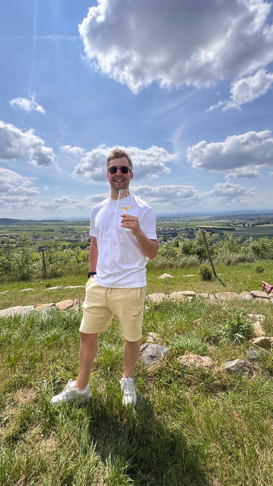 Anton Zhilin, founder of LOWINE, with a glass of white wine on a hillside