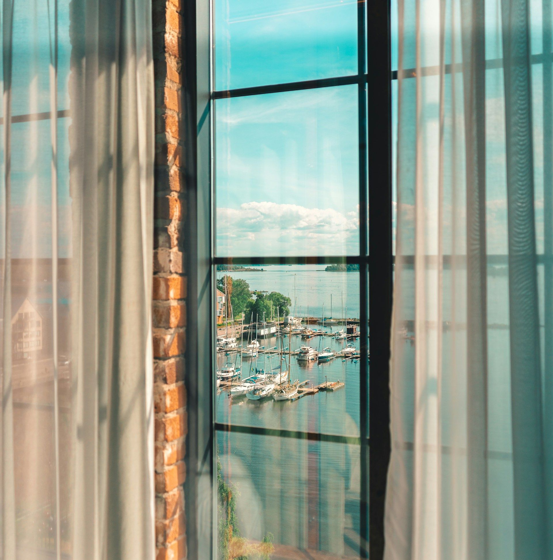 Utsikt över Västerås småbåtshamn och Mälaren genom ett hotellfönster.