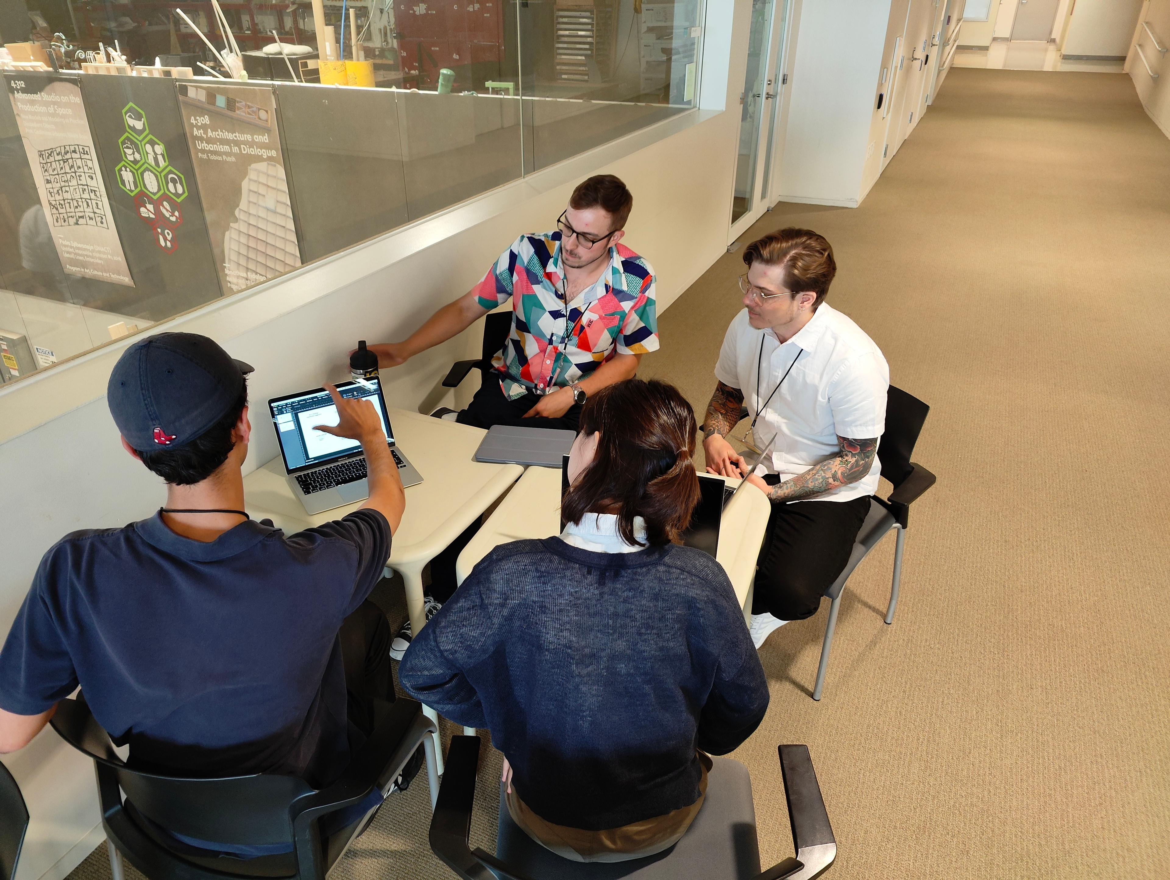 Photo of 4 conference attendees working at a table at the MIT Media Lab