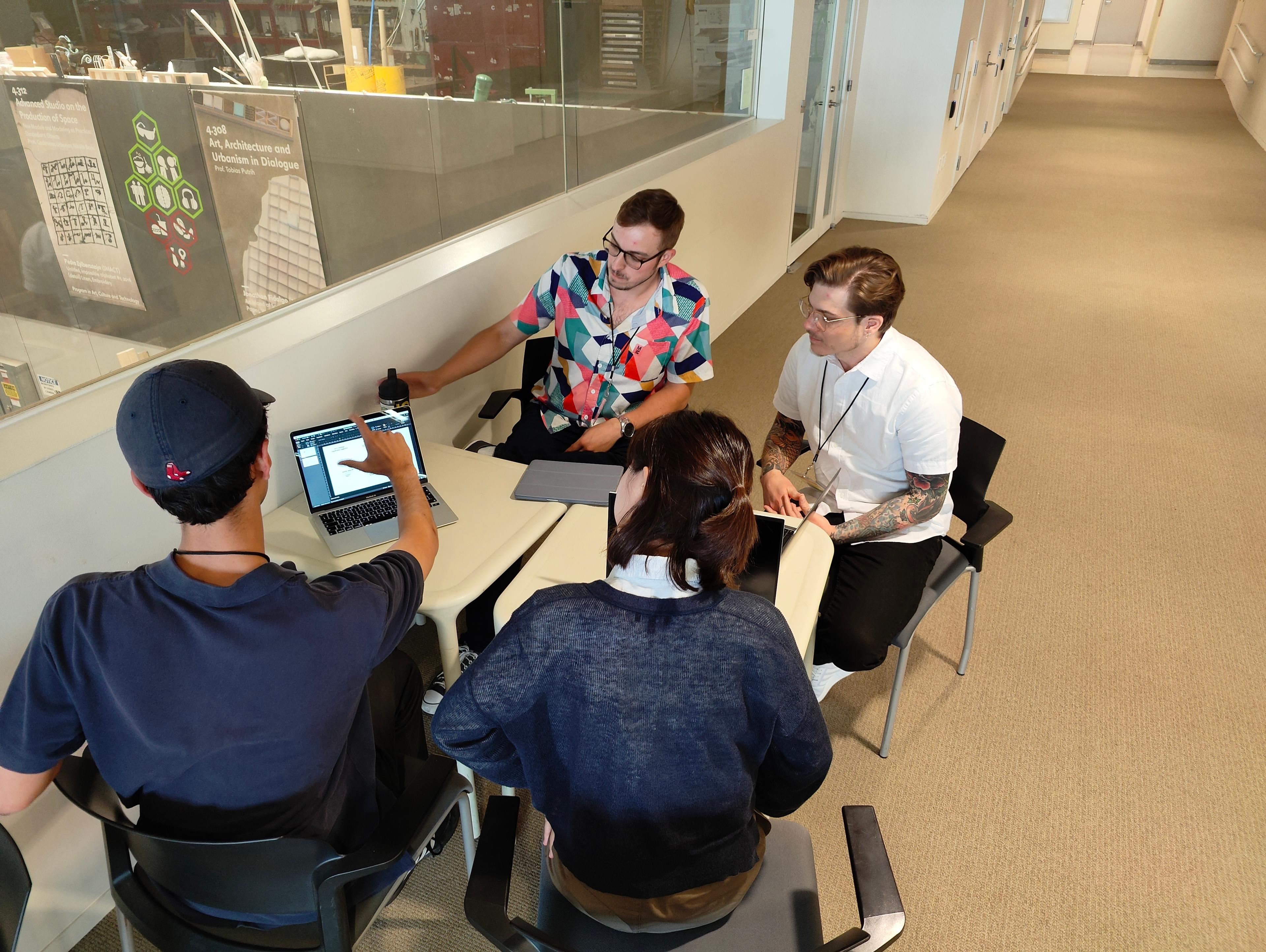 Photo of 4 conference attendees working at a table at the MIT Media Lab