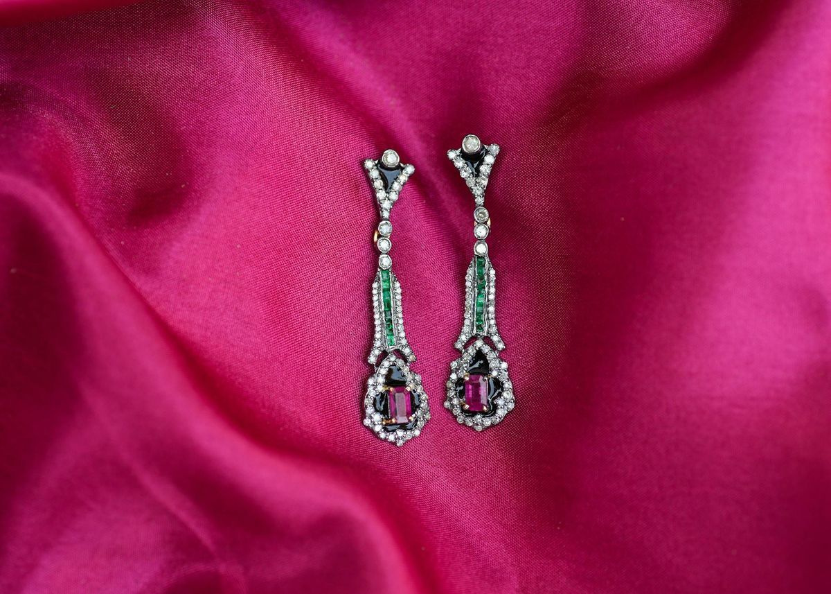 Luxurious emerald and ruby earrings with diamonds on a pink silk background. Perfect for high-end jewelry collections.