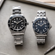 Two steel dive-watch styles compared on a collector's tray