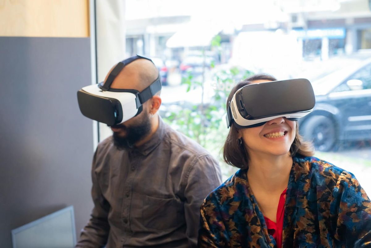 A man and woman enjoy virtual reality with VR headsets indoors. Captured in a lively setting.