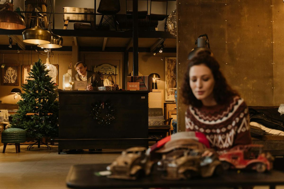 Woman shopping in a cozy store decorated for Christmas, with smiling salesman.