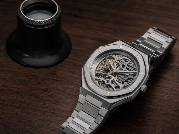 An integrated-bracelet haute-horlogerie watch being examined with a collector's loupe