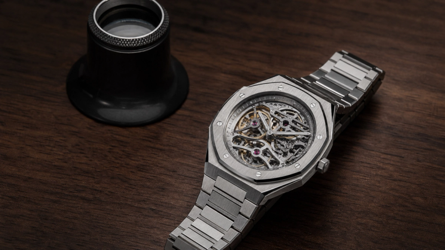 An integrated-bracelet haute-horlogerie watch being examined with a collector's loupe