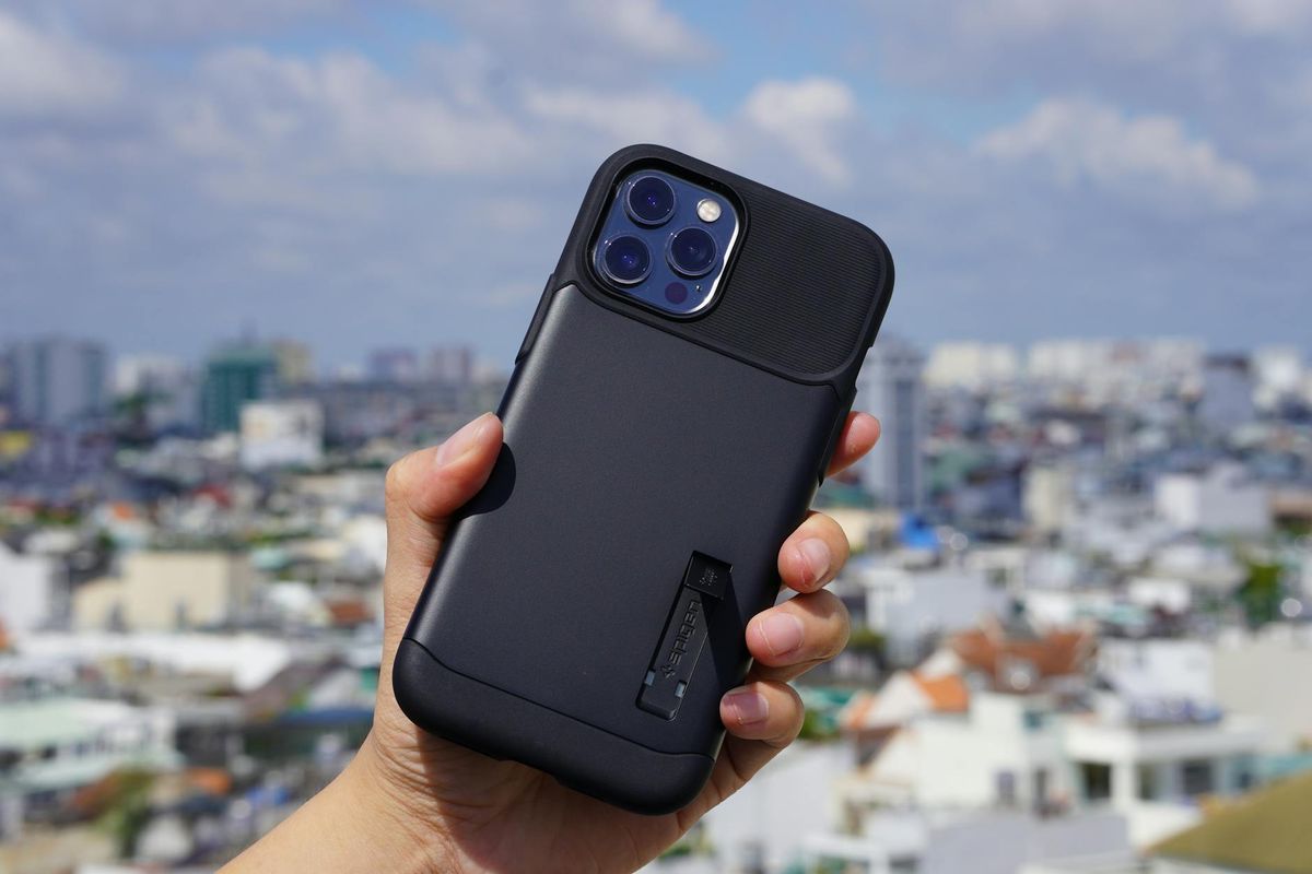 Close-up of a smartphone in a black case being held against a city skyline backdrop.