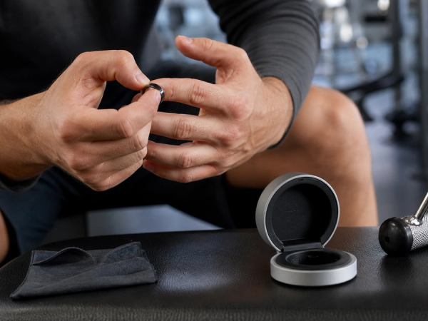 Smart ring placed beside gym gloves, sunscreen and a travel wash bag