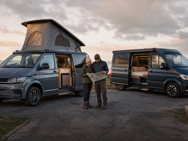 Travellers comparing two premium camper layouts at a coastal campsite