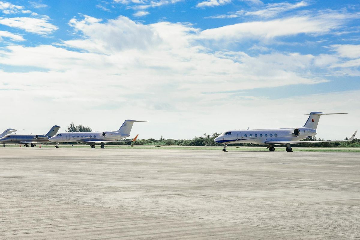 Private jets parked on an airport runway under a clear sky, highlighting luxury travel.