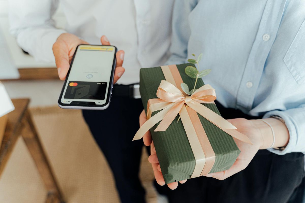 A person makes a contactless payment for a beautifully wrapped gift indoors.