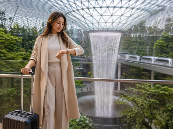 Premium transit traveller planning usable time beside Jewel Changi's indoor waterfall