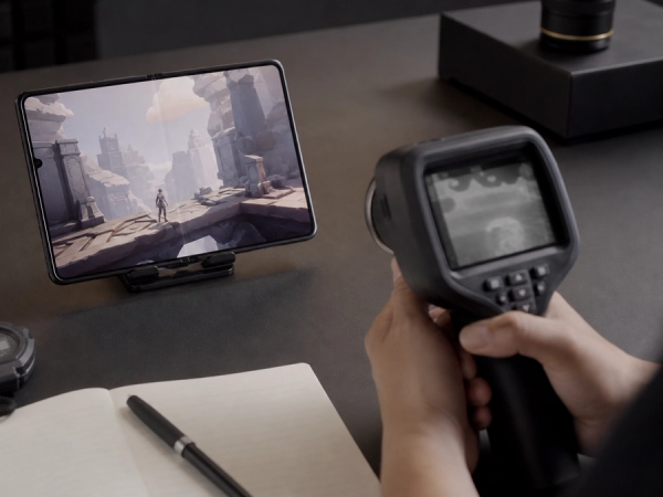 Unbranded foldable phone undergoing a controlled gaming performance test with a thermal camera.