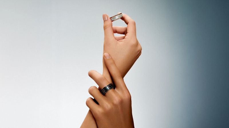 A close-up of a sophisticated smart ring being worn on a finger.