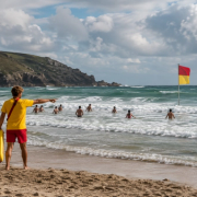 Lifeguards supervise swimmers between safety flags at a Cornish beach