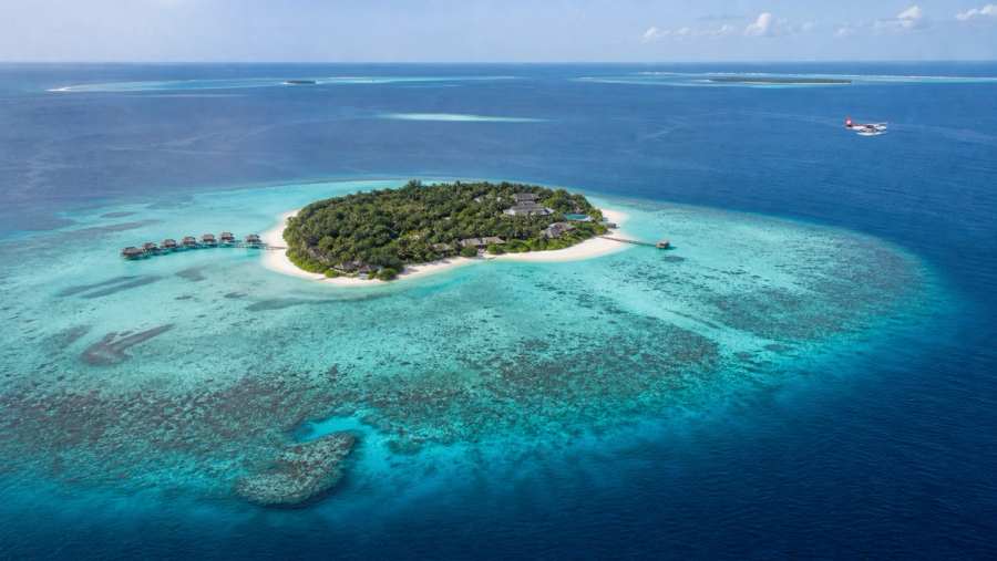 Aerial view of a private Maldives island, house reef and arriving seaplane