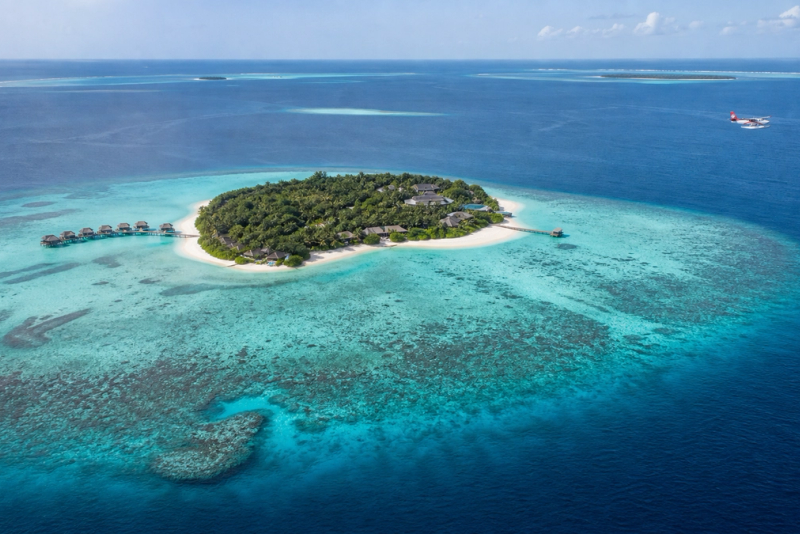 Aerial view of a private Maldives island, house reef and arriving seaplane