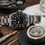 A pre-owned mechanical watch being examined beside service records and bracelet components