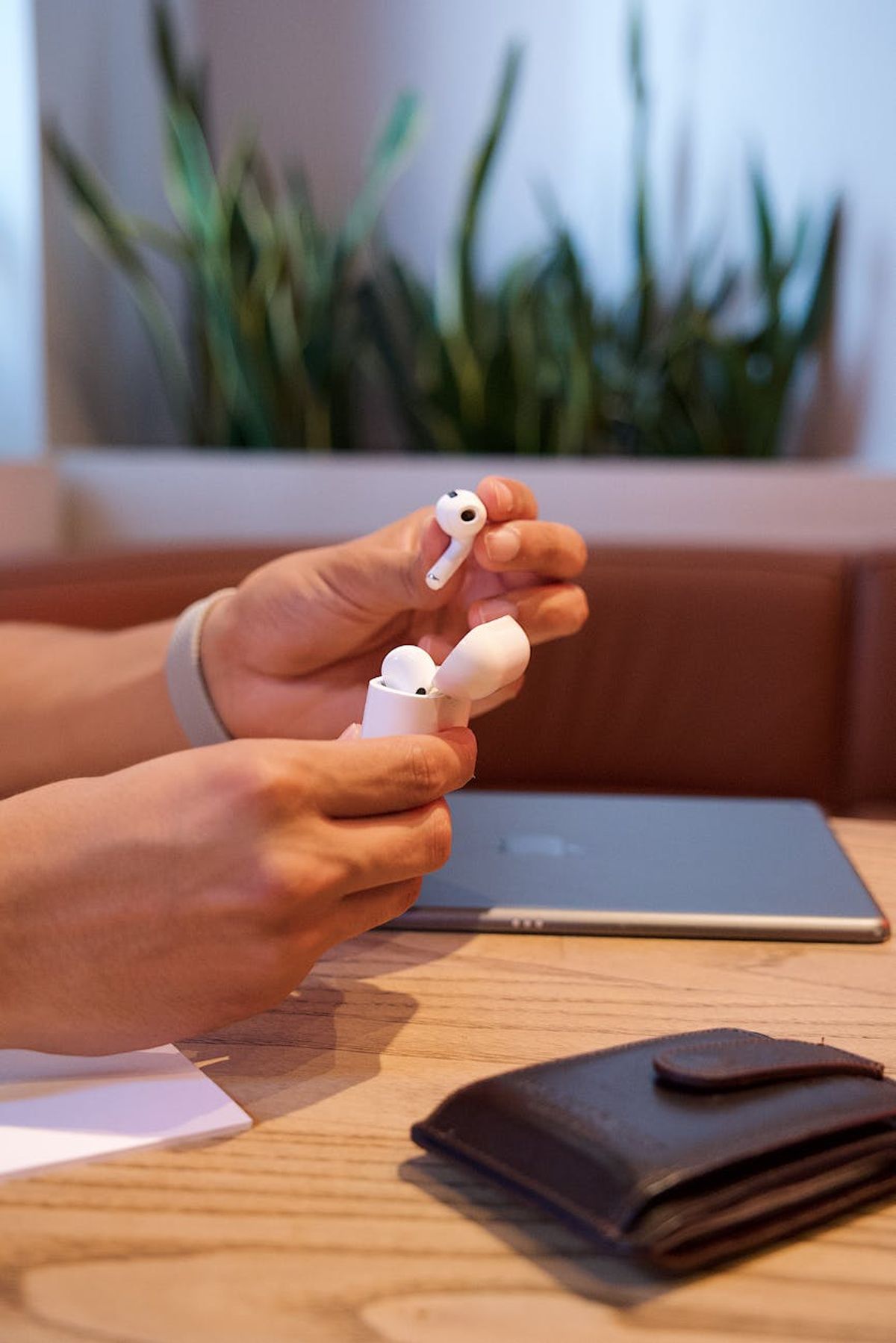 Close-up of hands holding wireless earbuds indoors, showcasing technology and lifestyle.