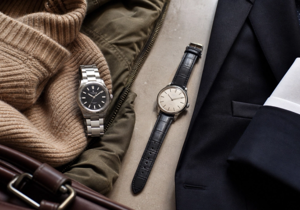 A refined steel sports watch silhouette and a slim leather dress watch silhouette arranged with tailoring and weekend clothing