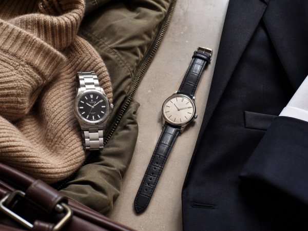 A refined steel sports watch silhouette and a slim leather dress watch silhouette arranged with tailoring and weekend clothing