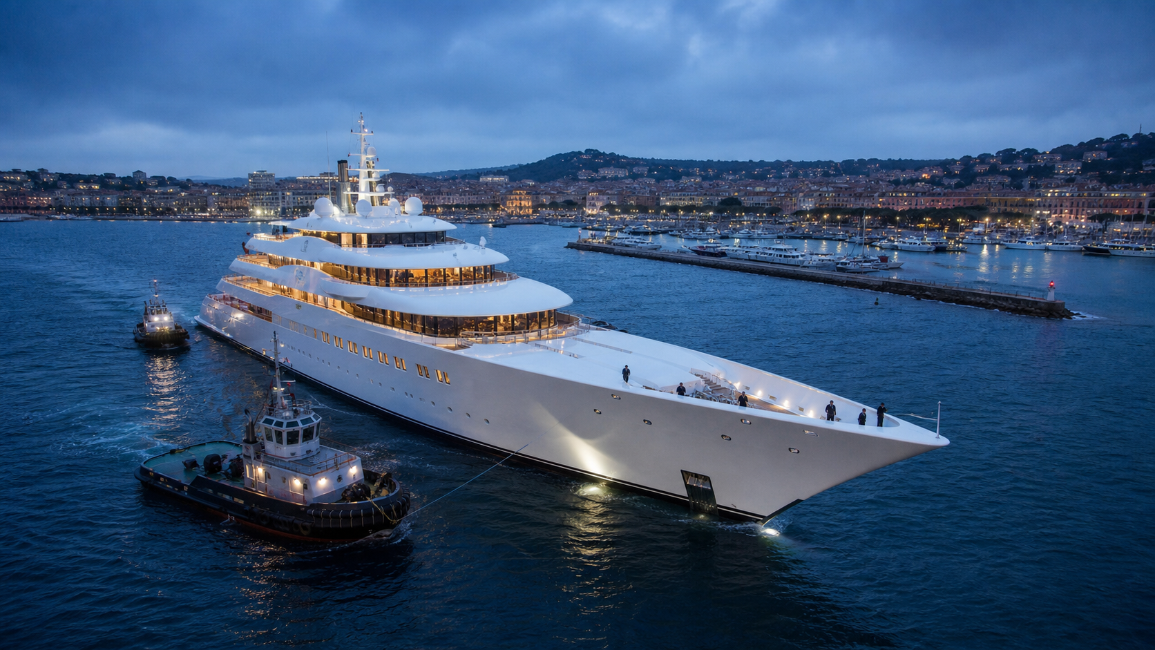A record-scale white superyacht entering harbour with tugboats and crew visible for scale