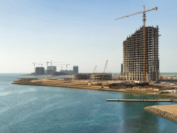editorial coastal photograph of Al Marjan Island in Ras Al Khaimah with a major resort tower visibly under construction