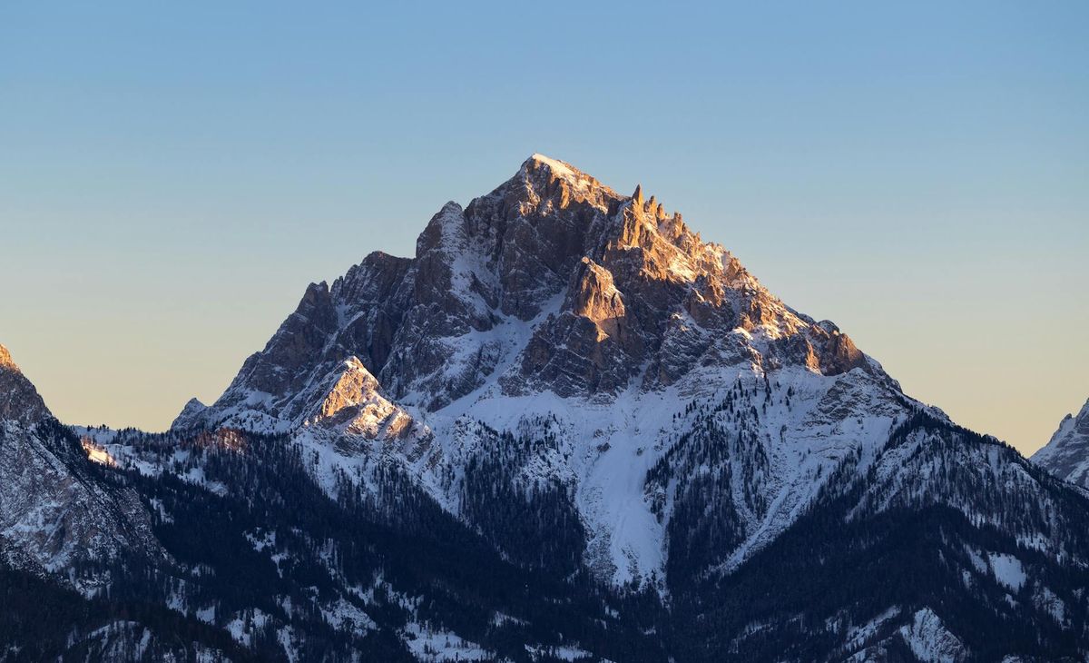 Experience the breathtaking beauty of a snow-covered mountain peak glowing under a vibrant sunset.