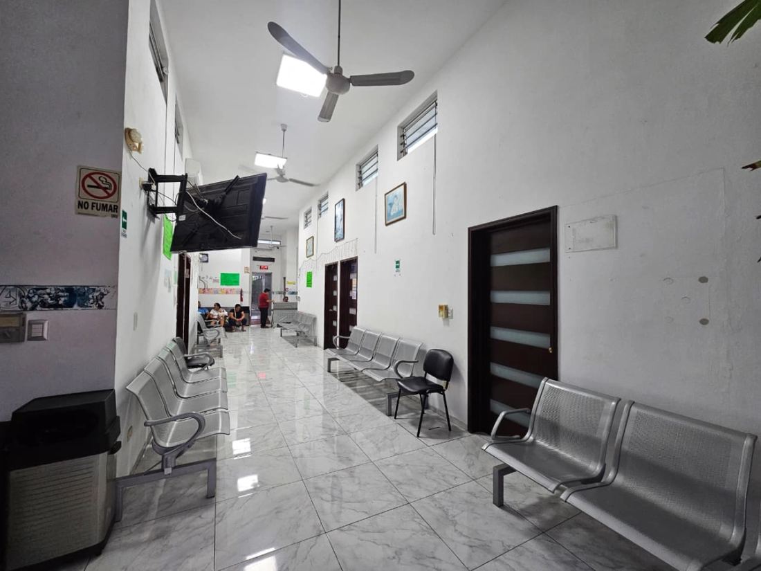 Corredor de espera con sillas alineadas frente a las puertas de los consultorios