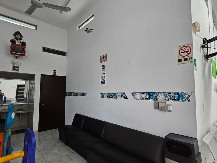 Sala de espera con sillón largo y sillas metálicas, junto al área infantil