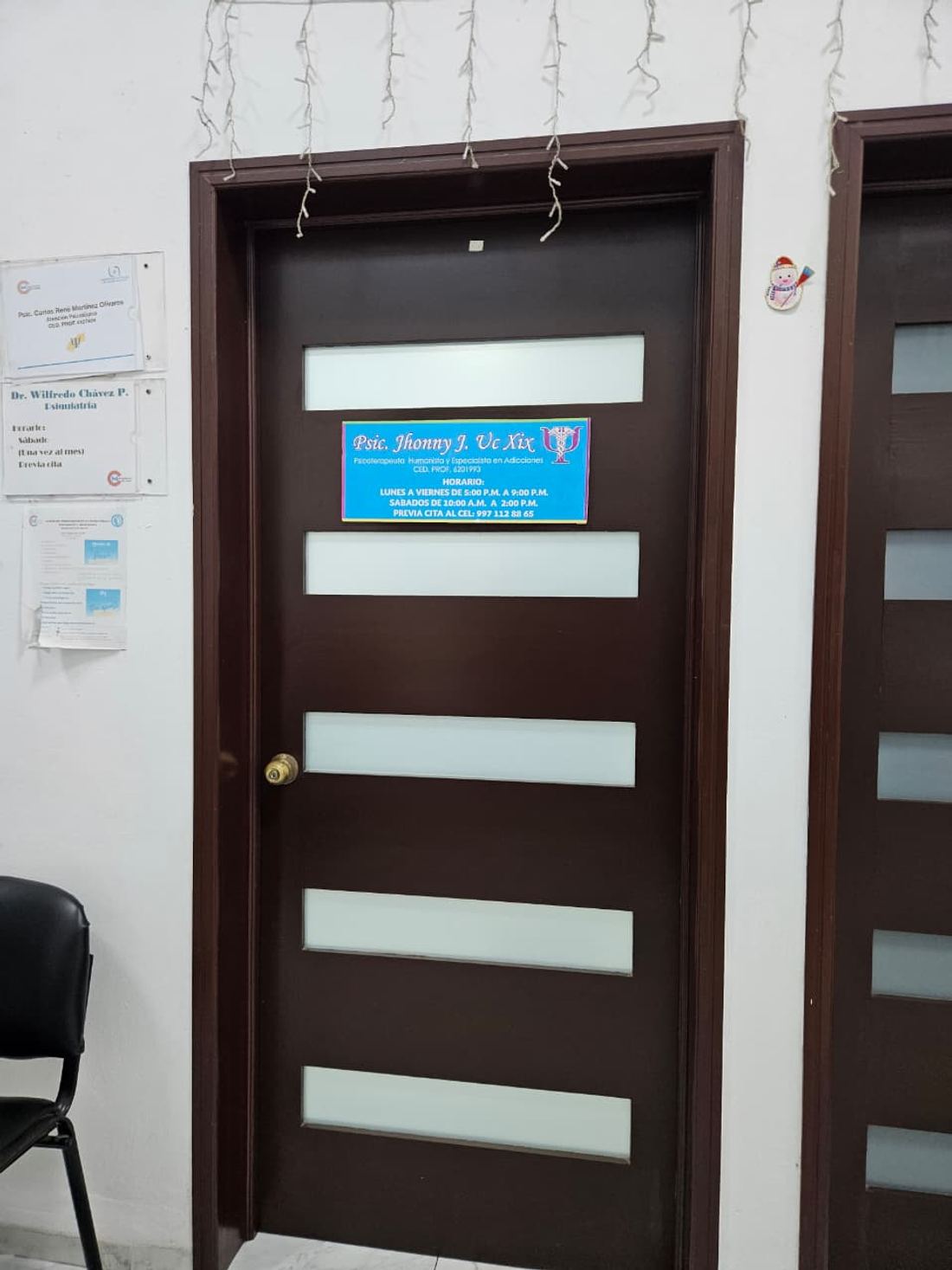Puerta del consultorio de psicoterapia del Psic. Jhonny Uc Xix, con su horario de atención rotulado