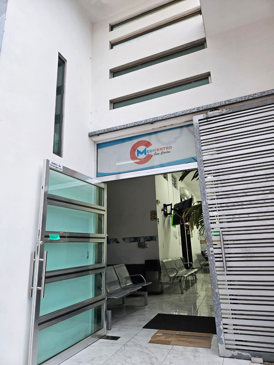 Acceso a la clínica con el logotipo de MEDICENTRO San Carlos sobre la entrada y la sala de espera al fondo